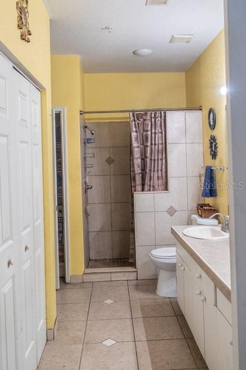 bathroom with toilet, a shower with curtain, tile walls, vanity, and tile patterned flooring