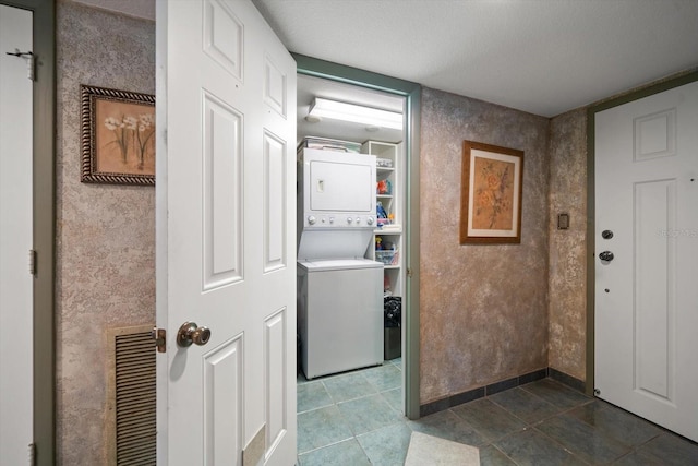 clothes washing area with tile patterned flooring and stacked washer / dryer