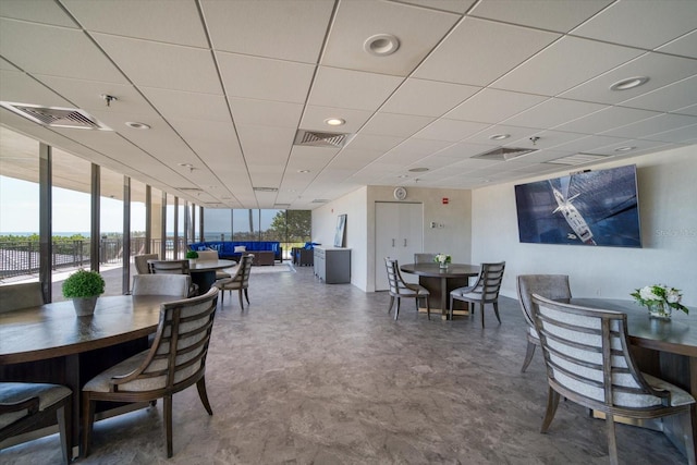 dining space featuring floor to ceiling windows and a drop ceiling