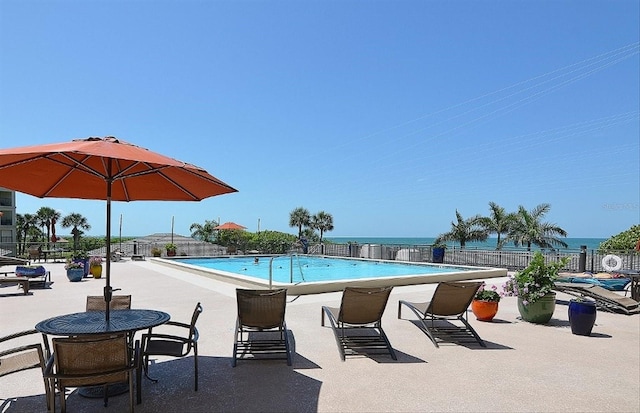 view of pool featuring a water view and a patio area