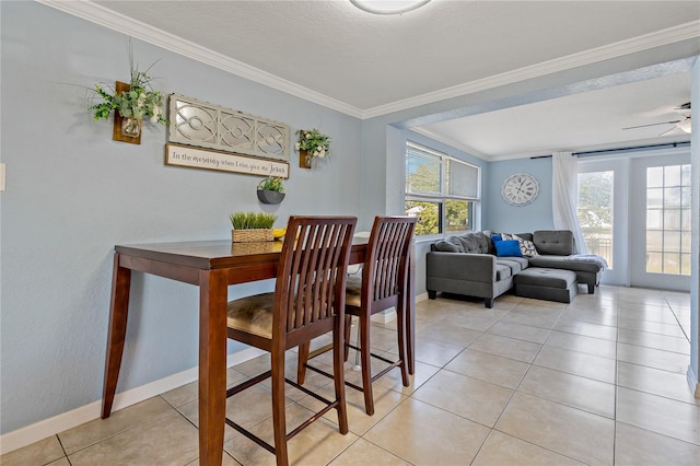 tiled dining area with ceiling fan, crown molding, and a textured ceiling