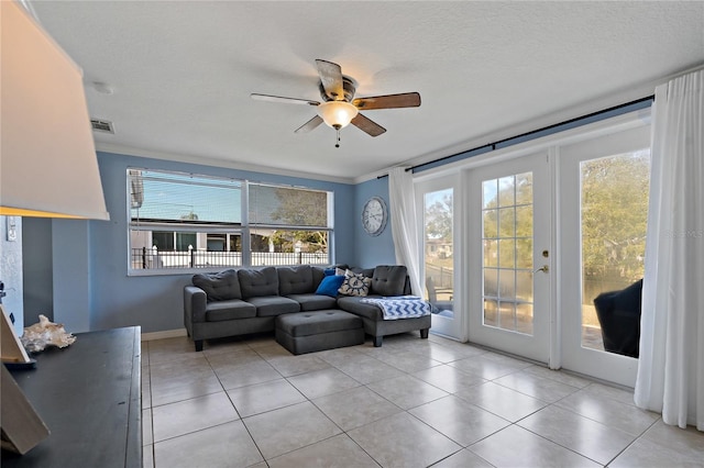 tiled living room featuring crown molding, ceiling fan, and a textured ceiling