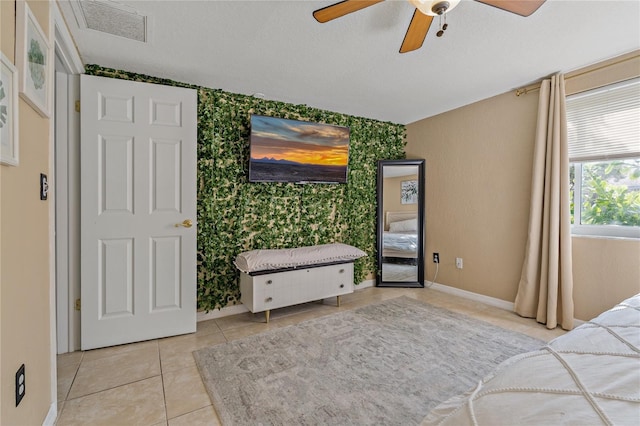 tiled bedroom with a textured ceiling and ceiling fan