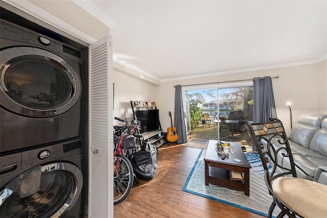 living room with stacked washer / drying machine, ornamental molding, and hardwood / wood-style floors