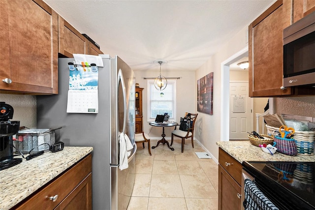 kitchen with stainless steel appliances, light tile patterned flooring, hanging light fixtures, and light stone countertops