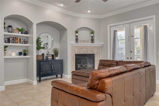 living room featuring a premium fireplace, crown molding, built in features, and french doors