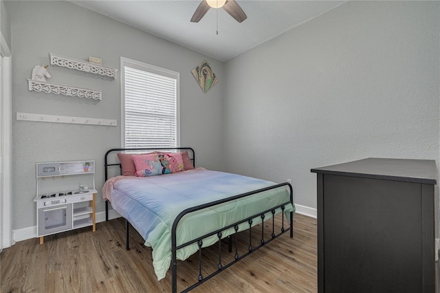 bedroom featuring ceiling fan, baseboards, and wood finished floors