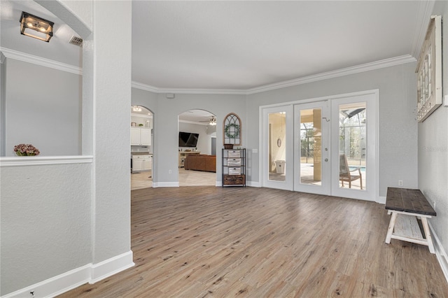 interior space featuring ornamental molding, arched walkways, and light wood finished floors