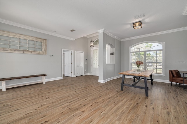 entrance foyer featuring baseboards, wood finished floors, visible vents, and crown molding