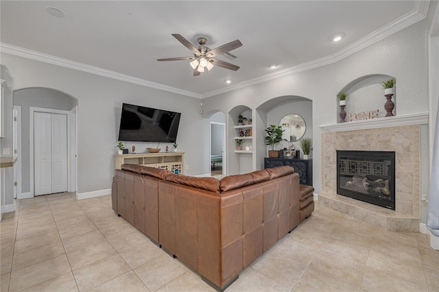 living area featuring light tile patterned floors, built in shelves, a high end fireplace, baseboards, and ornamental molding