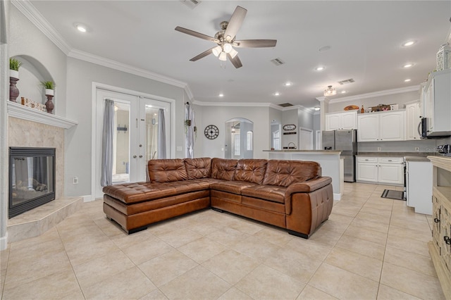 living area with ornamental molding, visible vents, arched walkways, and a tile fireplace