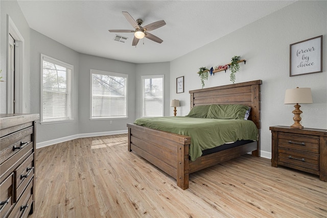 bedroom featuring a ceiling fan, baseboards, visible vents, and light wood finished floors