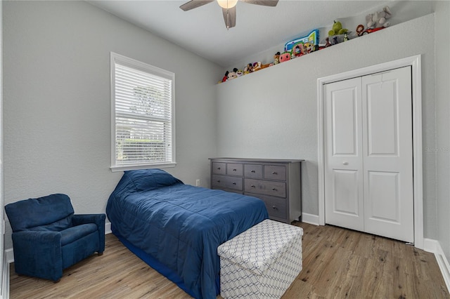 bedroom featuring a ceiling fan, a closet, baseboards, and wood finished floors