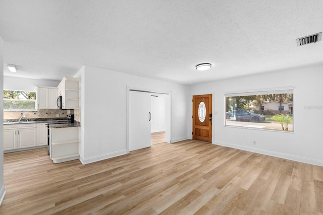 foyer with a textured ceiling, light wood-style flooring, and visible vents