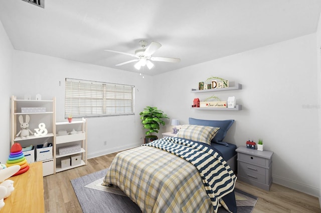 bedroom featuring light wood finished floors, a ceiling fan, and baseboards