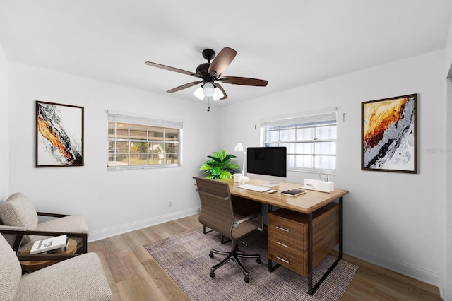 office area with light wood-type flooring, ceiling fan, and baseboards