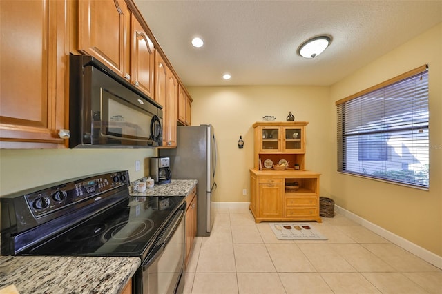 kitchen with light stone counters, light tile patterned floors, black appliances, and a textured ceiling