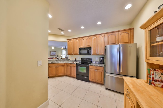 kitchen featuring sink, light tile patterned floors, butcher block countertops, and black appliances