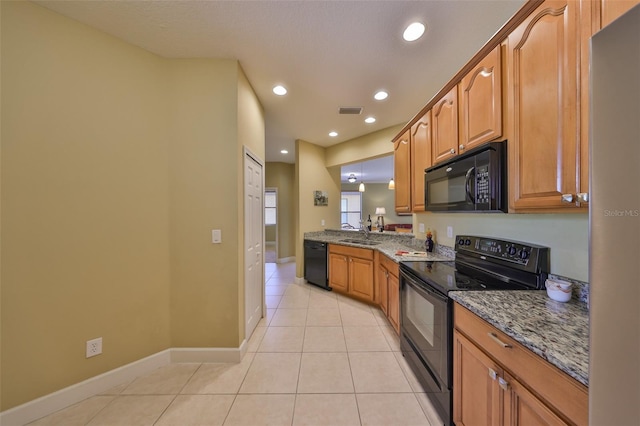 kitchen with light stone countertops, light tile patterned floors, black appliances, and sink