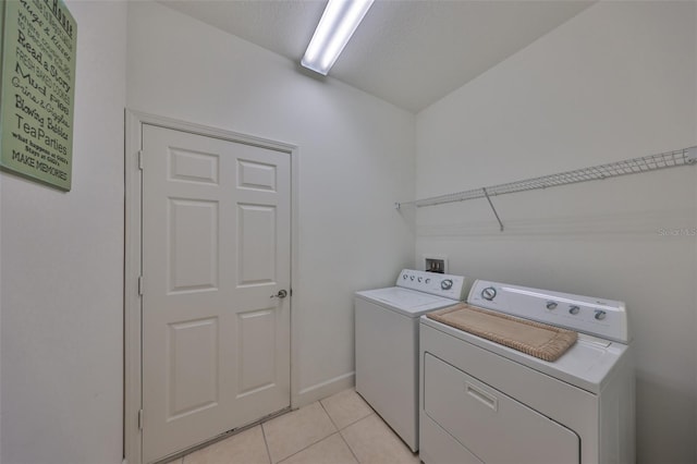 laundry room with light tile patterned floors, washing machine and dryer, and a textured ceiling