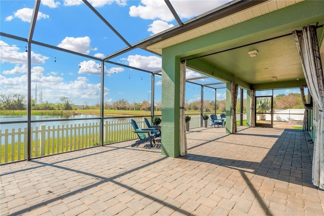 view of patio / terrace featuring a lanai and a water view