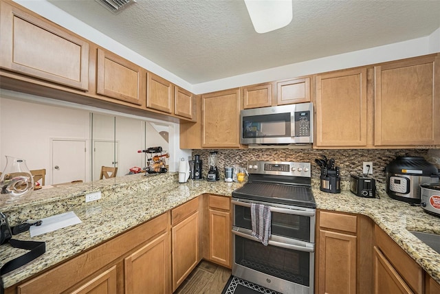 10944 Keys Gate Dr, Riverview, FL 33579 - kitchen featuring stainless steel appliances, a textured ceiling, backsplash, and light stone counters