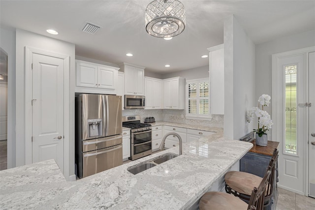 kitchen with a breakfast bar, sink, stainless steel appliances, kitchen peninsula, and white cabinets