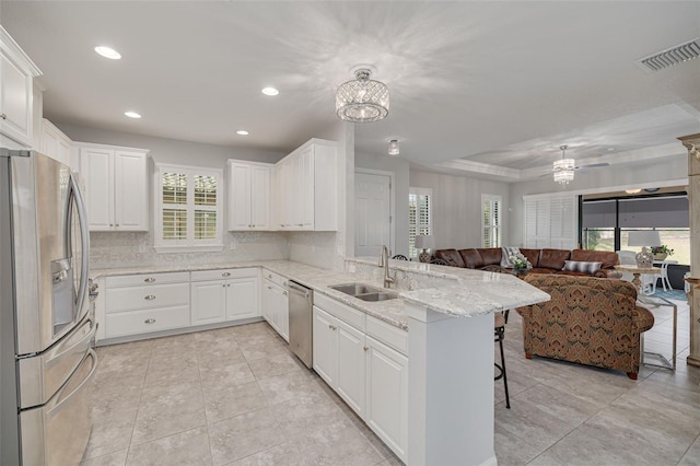 kitchen featuring a breakfast bar area, stainless steel appliances, white cabinetry, and kitchen peninsula