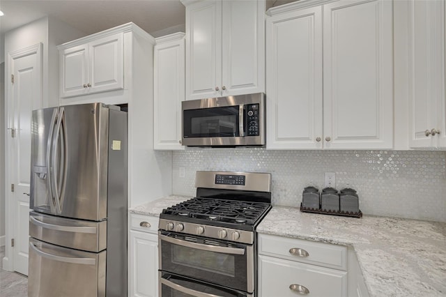 kitchen with appliances with stainless steel finishes, decorative backsplash, white cabinetry, and light stone countertops