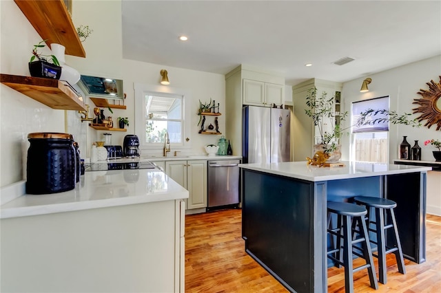 kitchen featuring sink, light wood-type flooring, a kitchen breakfast bar, a kitchen island, and stainless steel appliances