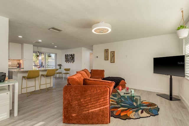 living room with a textured ceiling and light wood-type flooring