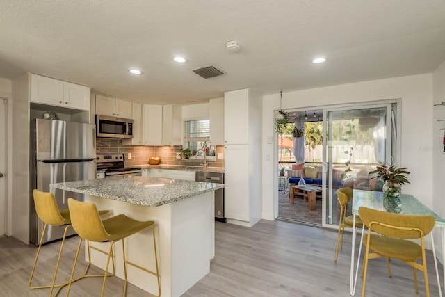 kitchen with stainless steel appliances, tasteful backsplash, a breakfast bar area, and white cabinets