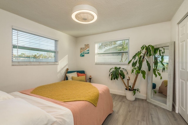 bedroom with a textured ceiling and light wood-type flooring