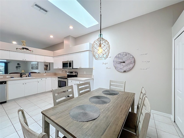 dining area featuring sink, a skylight, and light tile patterned flooring