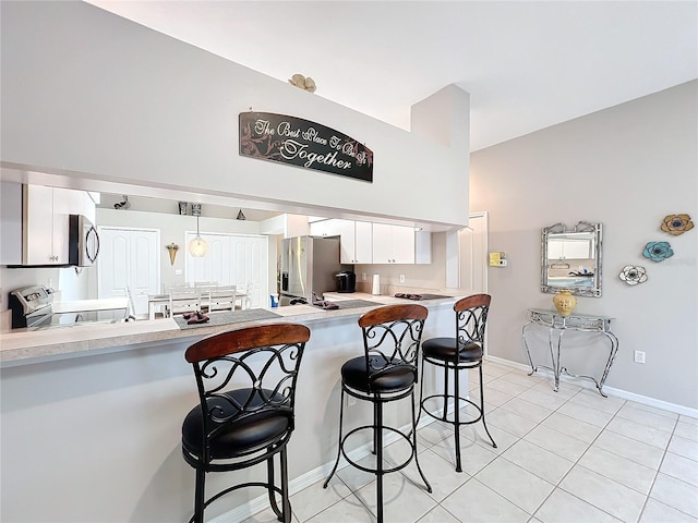 kitchen with a breakfast bar, hanging light fixtures, stainless steel appliances, white cabinets, and kitchen peninsula