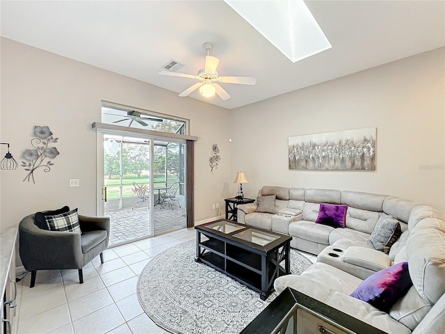 living room with ceiling fan, a skylight, and light tile patterned floors