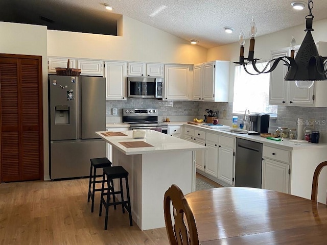 kitchen featuring pendant lighting, appliances with stainless steel finishes, a kitchen island, and white cabinets