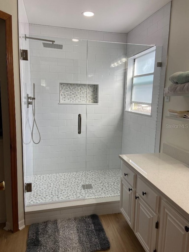 bathroom featuring vanity, wood-type flooring, and walk in shower