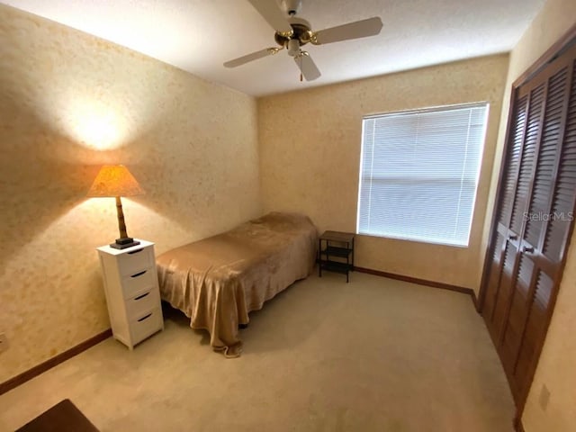 bedroom featuring ceiling fan, light colored carpet, and a closet