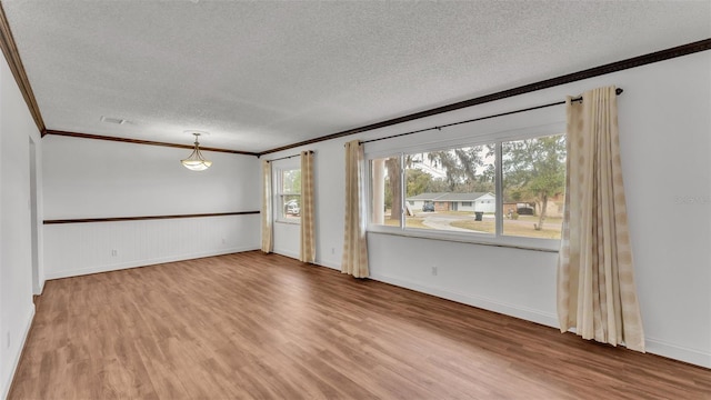 empty room featuring crown molding, wood-type flooring, and a textured ceiling