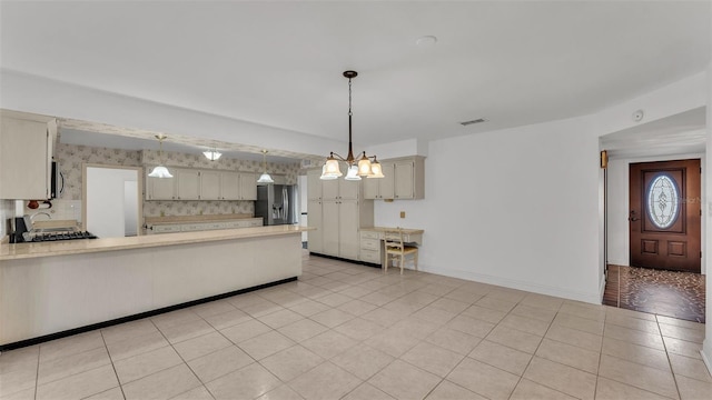 kitchen featuring stainless steel appliances, hanging light fixtures, light tile patterned floors, and backsplash