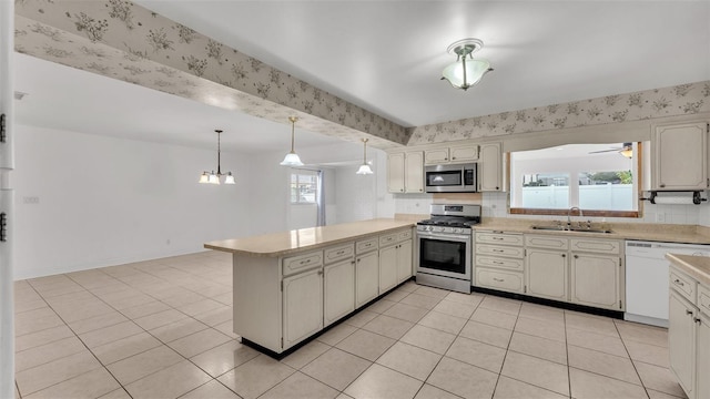 kitchen featuring sink, hanging light fixtures, stainless steel appliances, a healthy amount of sunlight, and kitchen peninsula