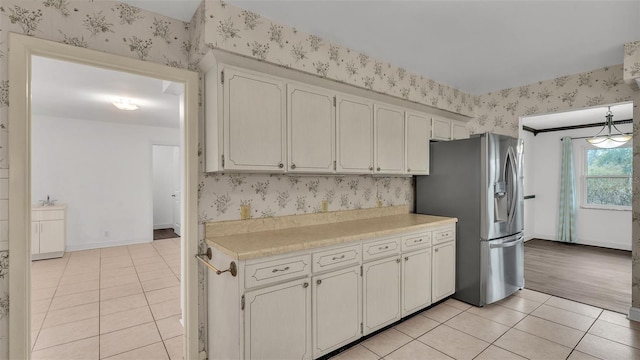 kitchen with light tile patterned floors, decorative light fixtures, stainless steel fridge, and white cabinets