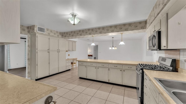 kitchen with pendant lighting, sink, appliances with stainless steel finishes, light tile patterned flooring, and decorative backsplash