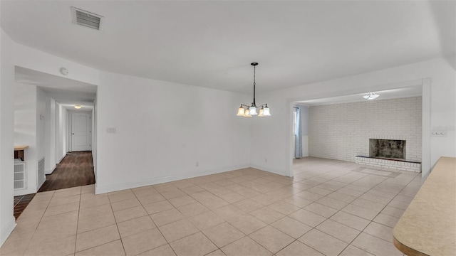 interior space featuring an inviting chandelier, a brick fireplace, and light tile patterned floors