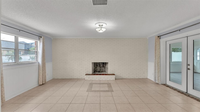 unfurnished living room with french doors, a textured ceiling, light tile patterned floors, brick wall, and a fireplace