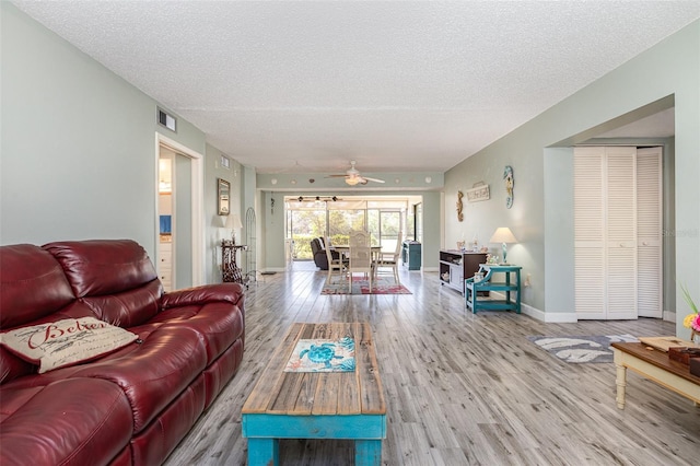 living room featuring ceiling fan, wood-type flooring, and a textured ceiling