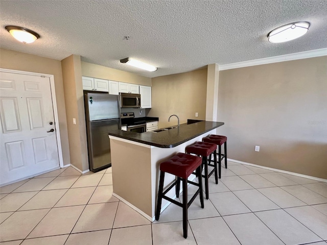 kitchen featuring sink, a breakfast bar, white cabinetry, stainless steel appliances, and kitchen peninsula