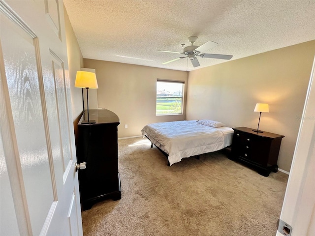 carpeted bedroom with ceiling fan and a textured ceiling