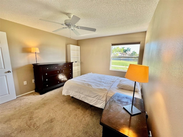 bedroom with ceiling fan, light colored carpet, and a textured ceiling